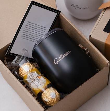 Caja kraft con vaso negro personalizado con nombre, chocolates y una tarjeta enmarcada