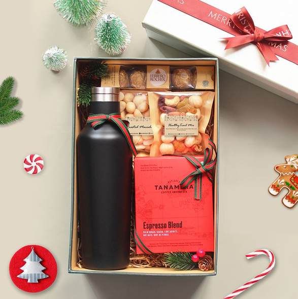Kit en caja abierta con termo negro, nueces, café y chocolates, junto a una cinta roja