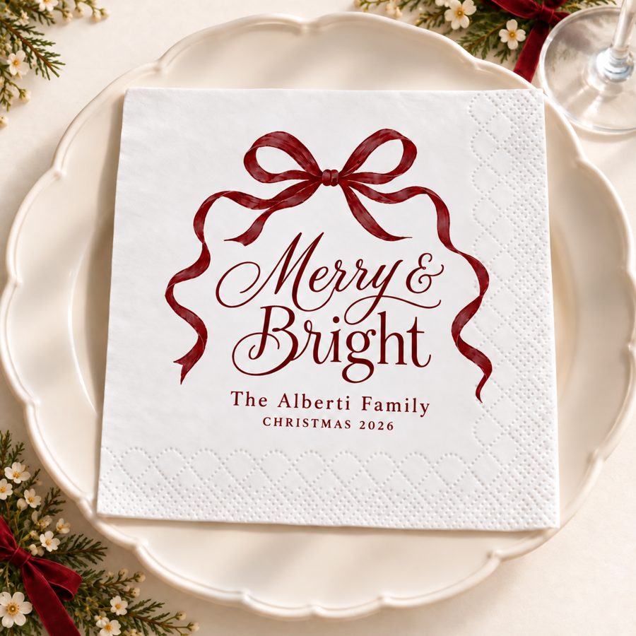 Servilleta blanca con un lazo vino y la frase Merry and Bright, sobre un plato de porcelana