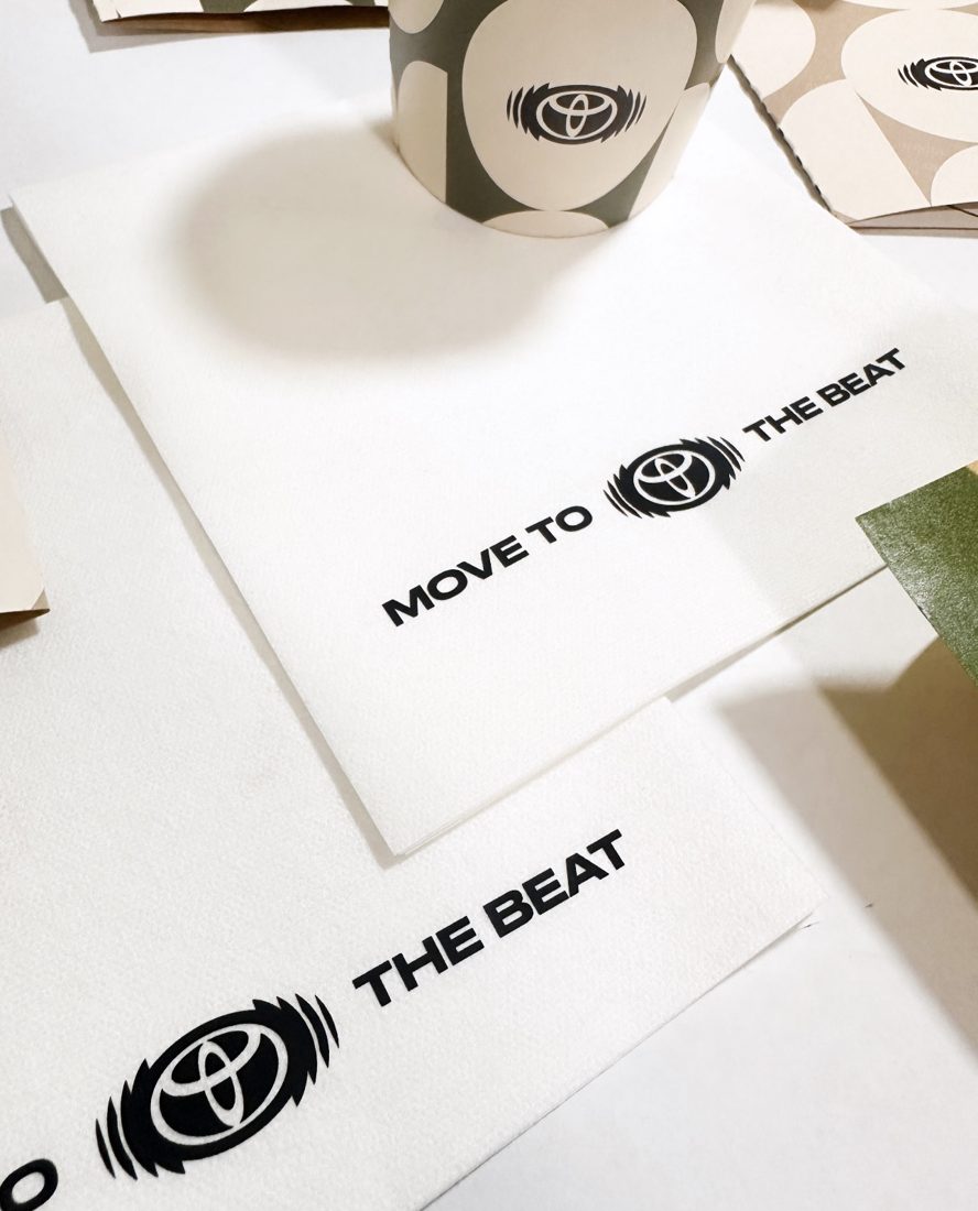 Servilletas blancas con logo corporativo impreso junto a vaso de papel personalizado