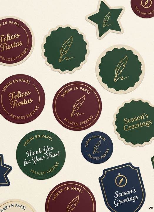 Stickers redondos y con forma de estrella y escudo en verde, vino y azul, con la frase Felices Fiestas